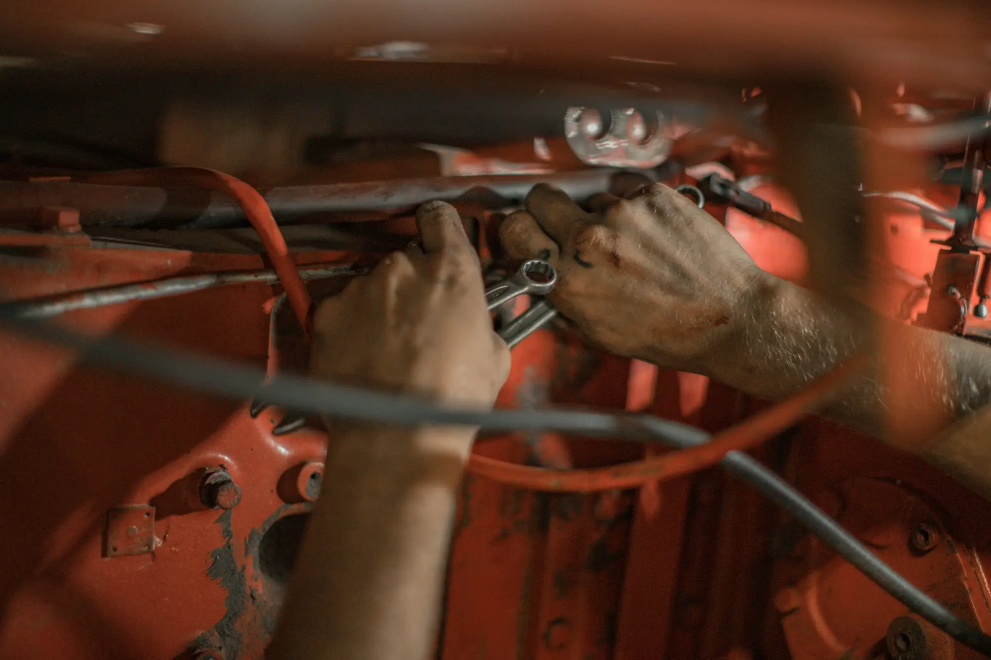Mechanic's hands repairing wiring inside a broken machine