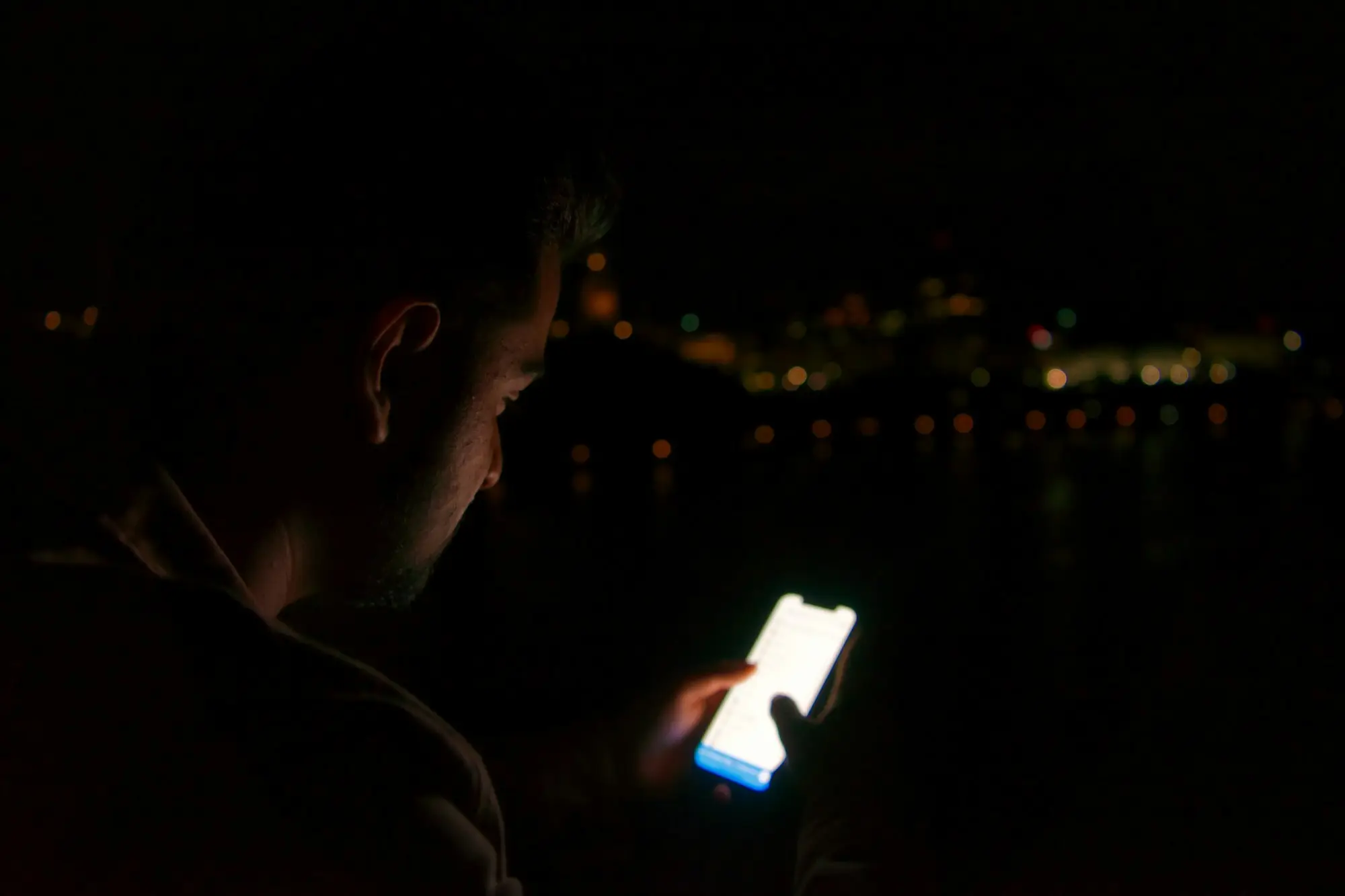 Business owner checking a banking app on a phone in the dark